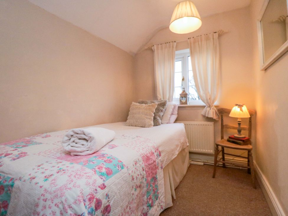 A bedroom with a single bed and a lamp at Jasmine Cottage in Dalton Near Thirsk