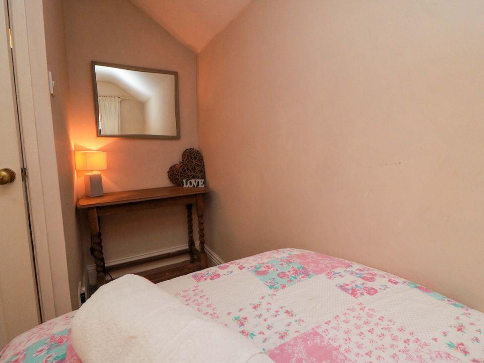 A bedroom with a bed and a mirror at Jasmine Cottage Dalton Near Thirsk