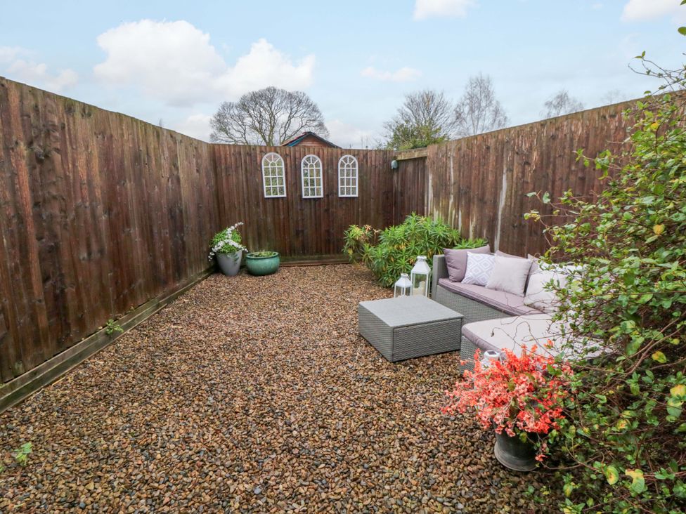 A garden with gravel, sofa, coffee table and planters at Jasmine Cottage in Dalton Near Thirsk