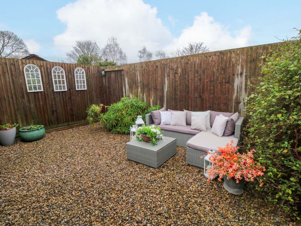 An outdoor seating area with sofa and flower pots at Jasmine Cottage Dalton Near Thirsk
