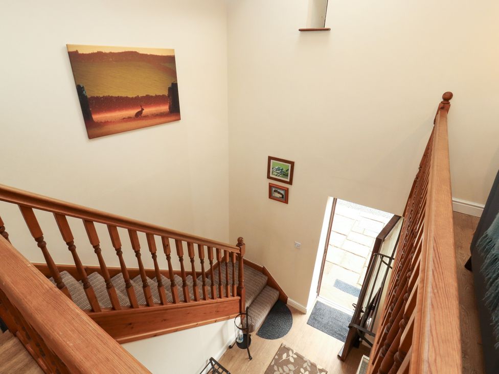 A staircase with artwork on the wall at Hayloft Cottage in Bolton Low Houses
