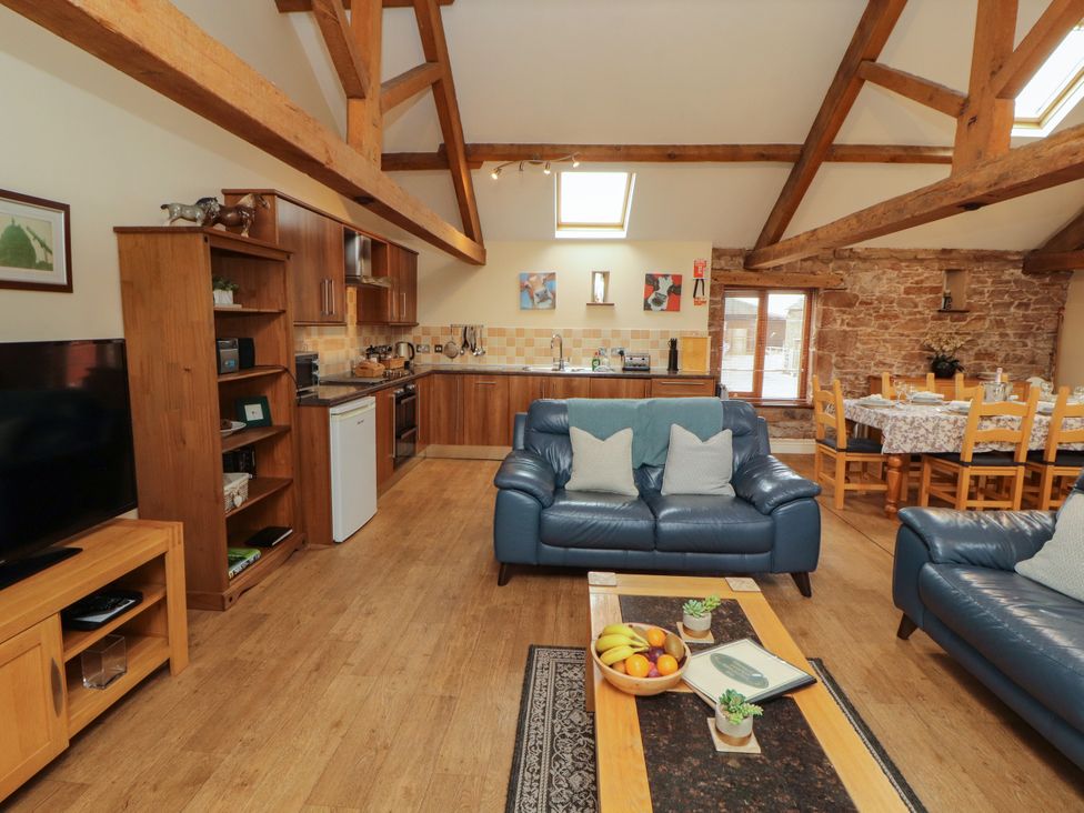 A living room with a sofa and dining area at Hayloft Cottage in Bolton Low Houses