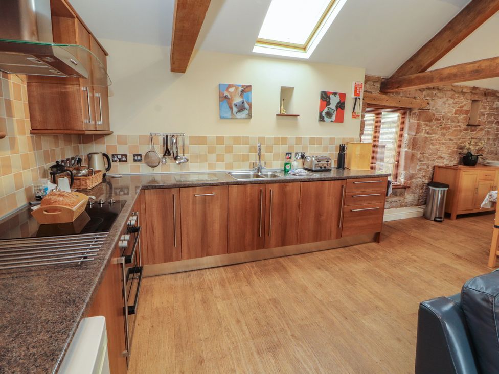 A kitchen with wooden cabinets and a sink at Hayloft Cottage Bolton Low Houses