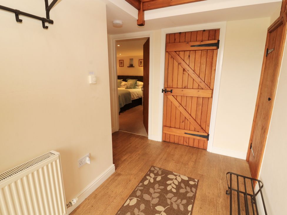 A hallway with a coat rack and a door at Hayloft Cottage Bolton Low Houses