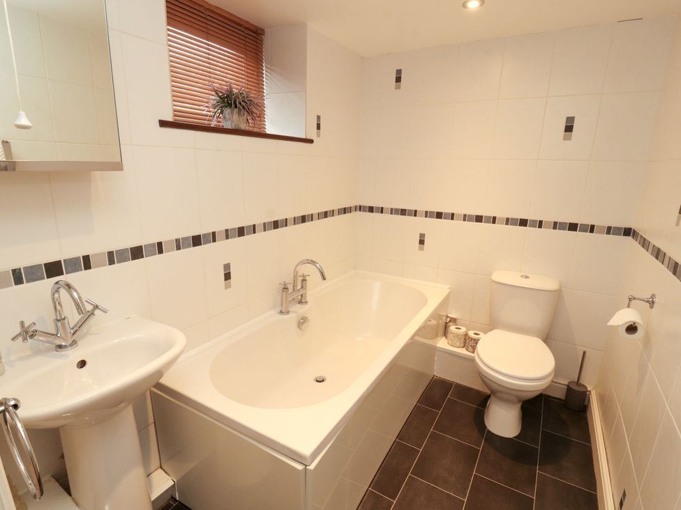 A bathroom with a bathtub, sink, and toilet at Hayloft Cottage in Bolton Low Houses
