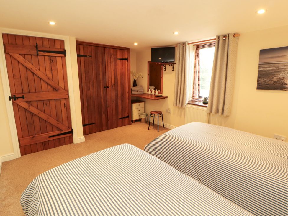 A bedroom with two beds and a wardrobe at Hayloft Cottage Bolton Low Houses