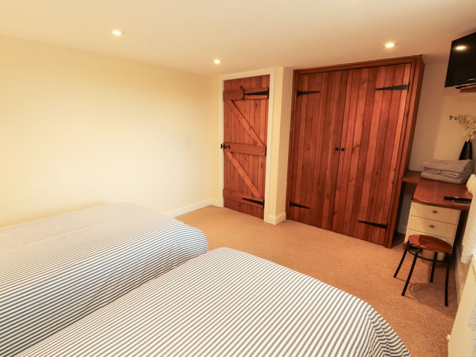 A bedroom with two beds and wooden furniture at Hayloft Cottage Bolton Low Houses