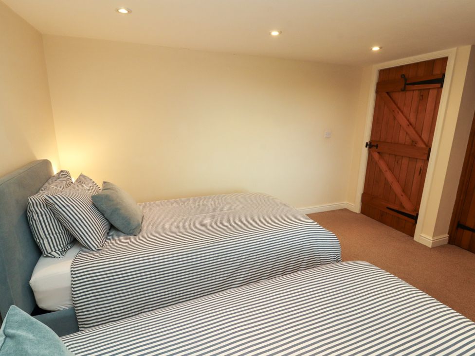 A bedroom with two beds and a wooden door at Hayloft Cottage Bolton Low Houses