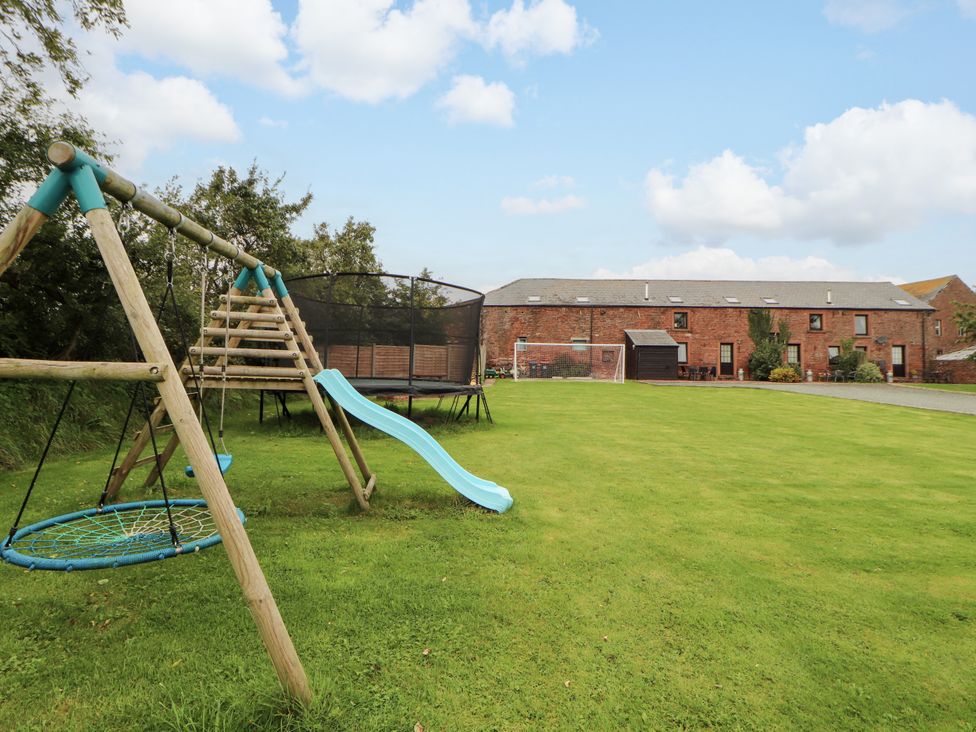 An outdoor area with a swing set and trampoline at Hayloft Cottage Bolton Low Houses