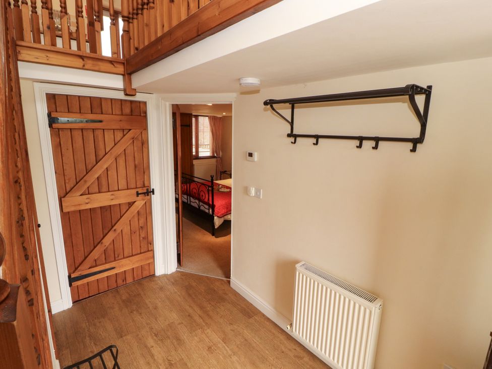A hallway with a wooden door, coat rack, and radiator at Horseshoe Cottage in Bolton Low Houses