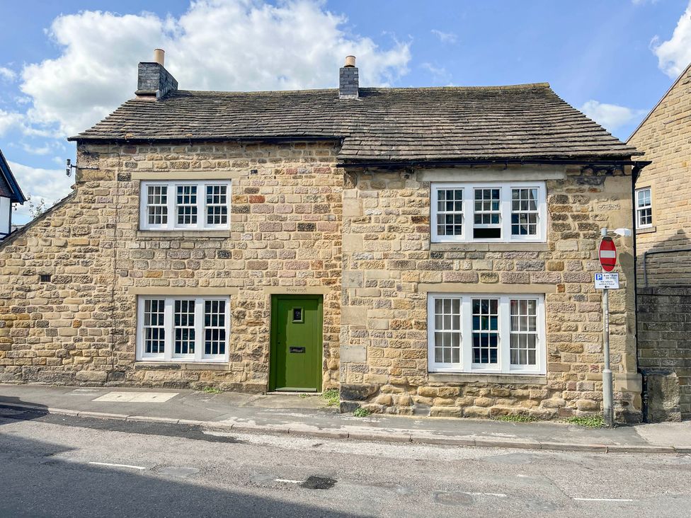 A stone house with multiple windows and a green door at Stonecroft in Bakewell