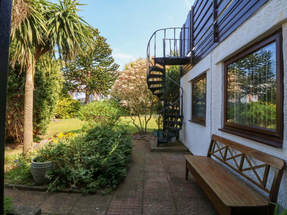 A garden with a spiral staircase and a wooden bench at Boathouse in Deganwy near Llandudno