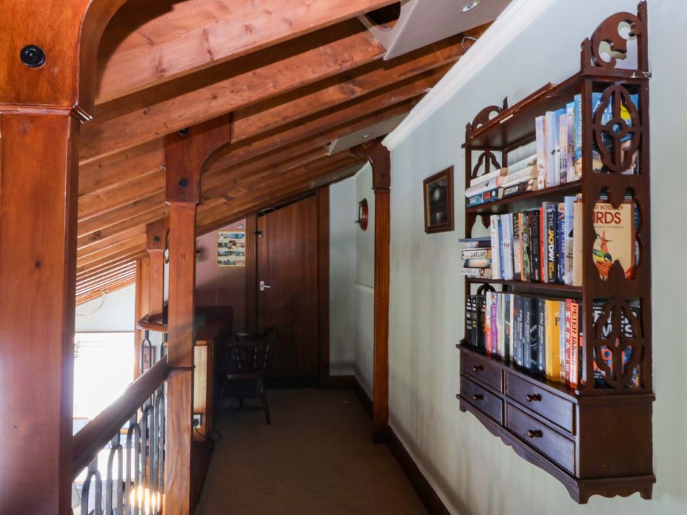 A hallway with a bookshelf and wooden beams at Boathouse in Deganwy near Llandudno