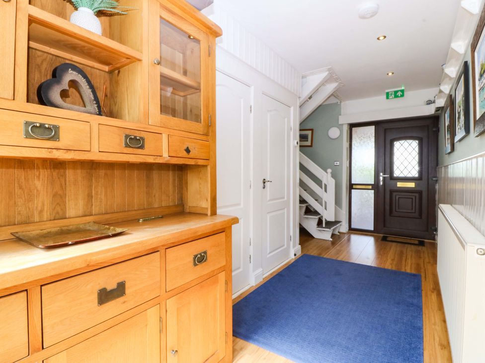 A hallway with a wooden cabinet and stairs at Boathouse in Deganwy near Llandudno