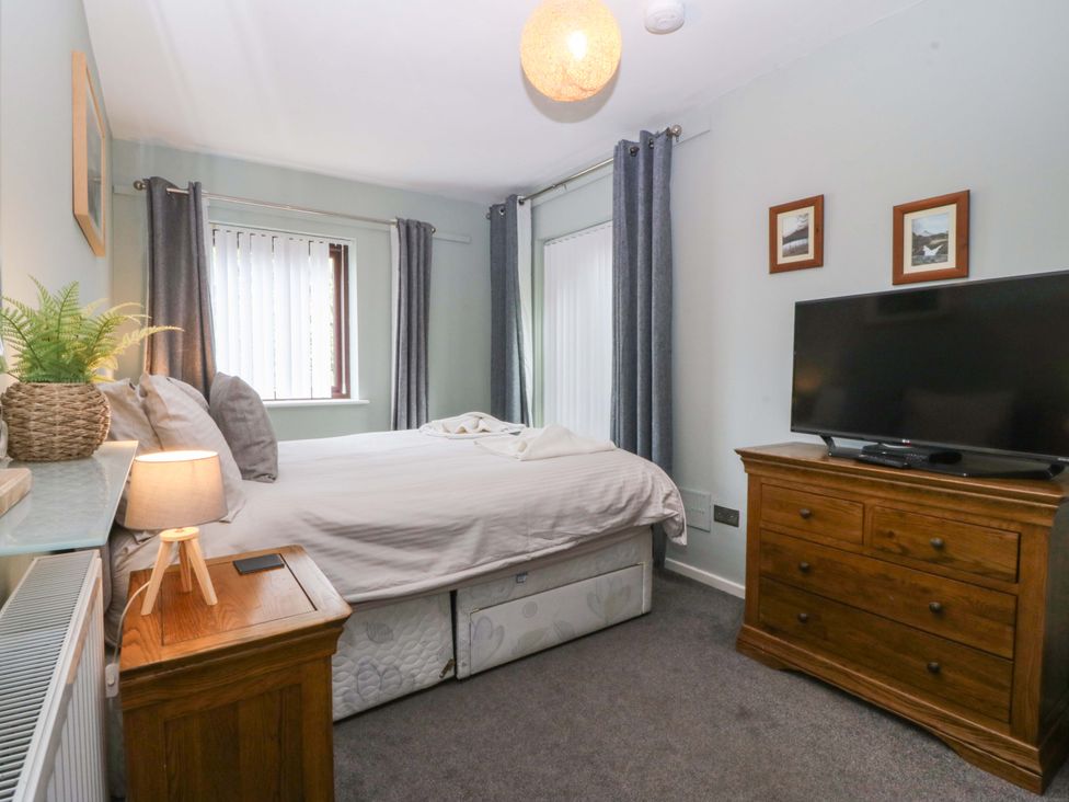 A bedroom with a bed, dresser, and television at Boathouse in Deganwy near Llandudno