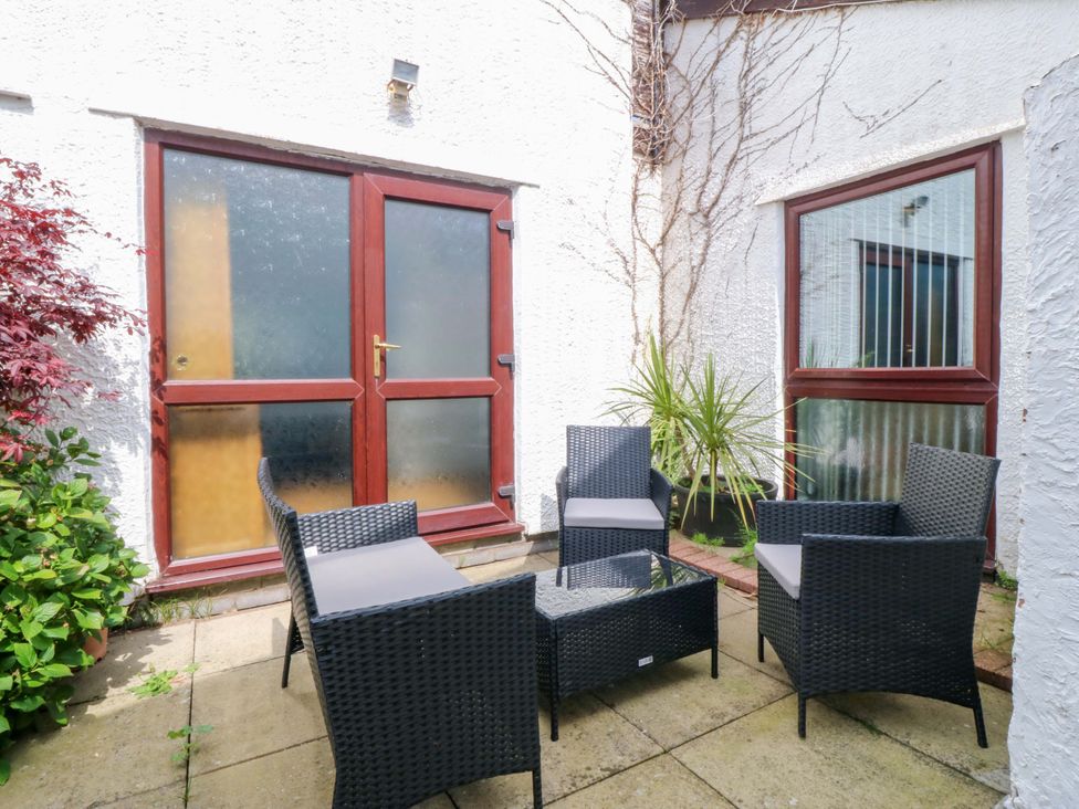 A patio with outdoor seating and a glass table at Boathouse in Deganwy near Llandudno