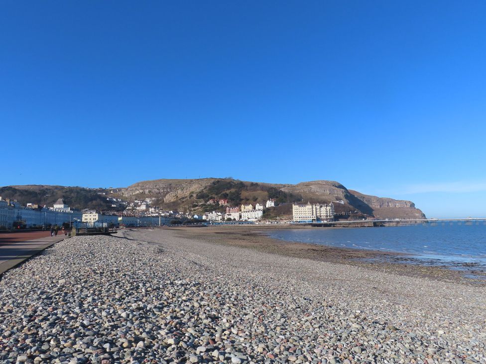 A beach with pebbles and buildings along the shore at Boathouse in Deganwy near Llandudno