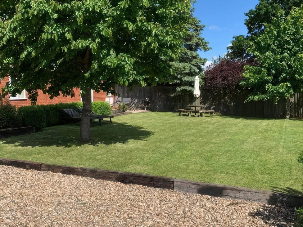 A garden with a tree and seating area at The Barn Ivy Cottage, Kexby near York