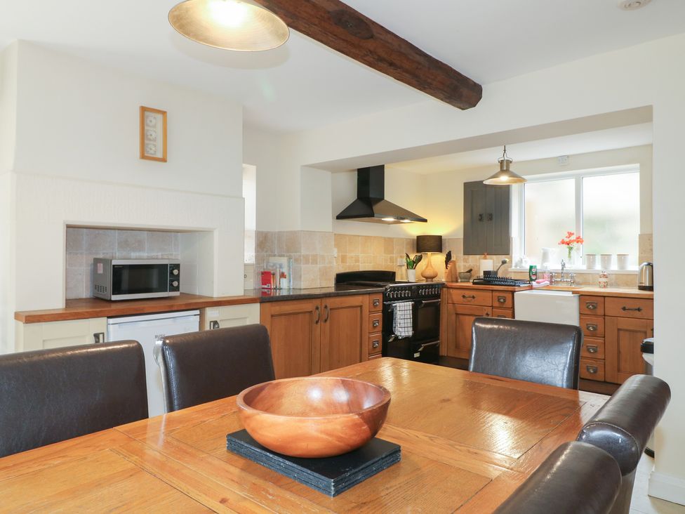 A kitchen with a table and chairs along with a microwave and stove at Ash House in Alton near Alton Towers