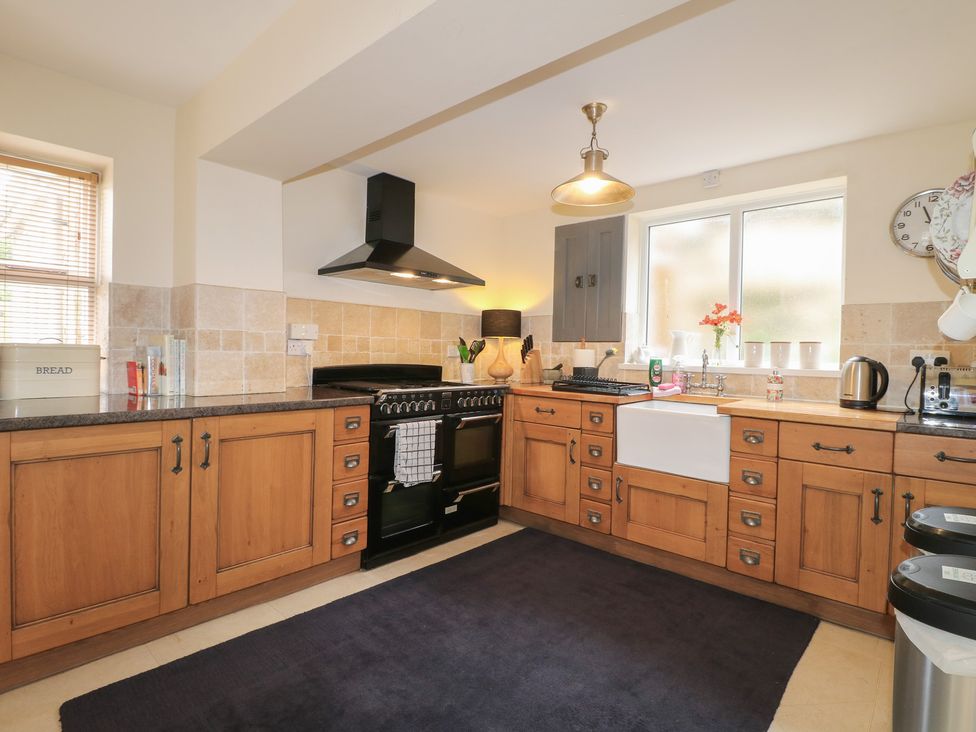 A kitchen with cabinets and a cooker at Ash House in Alton near Alton Towers