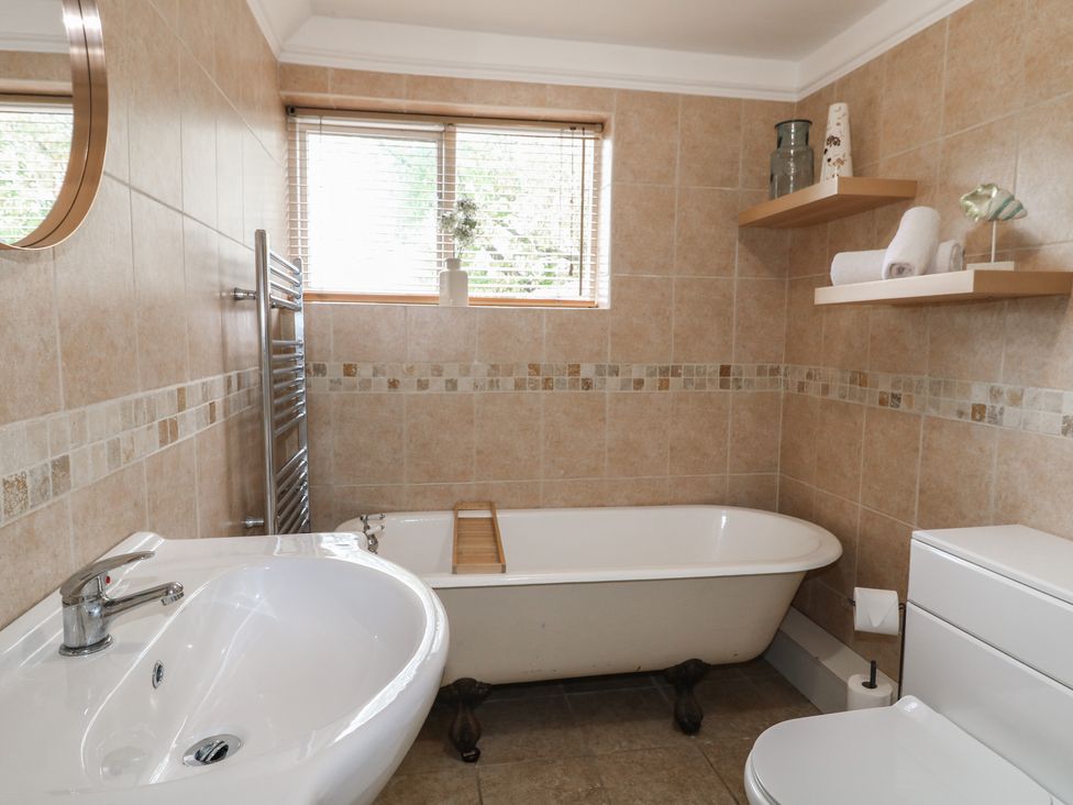 A bathroom with a bathtub and a towel shelf at Ash House in Alton near Alton Towers