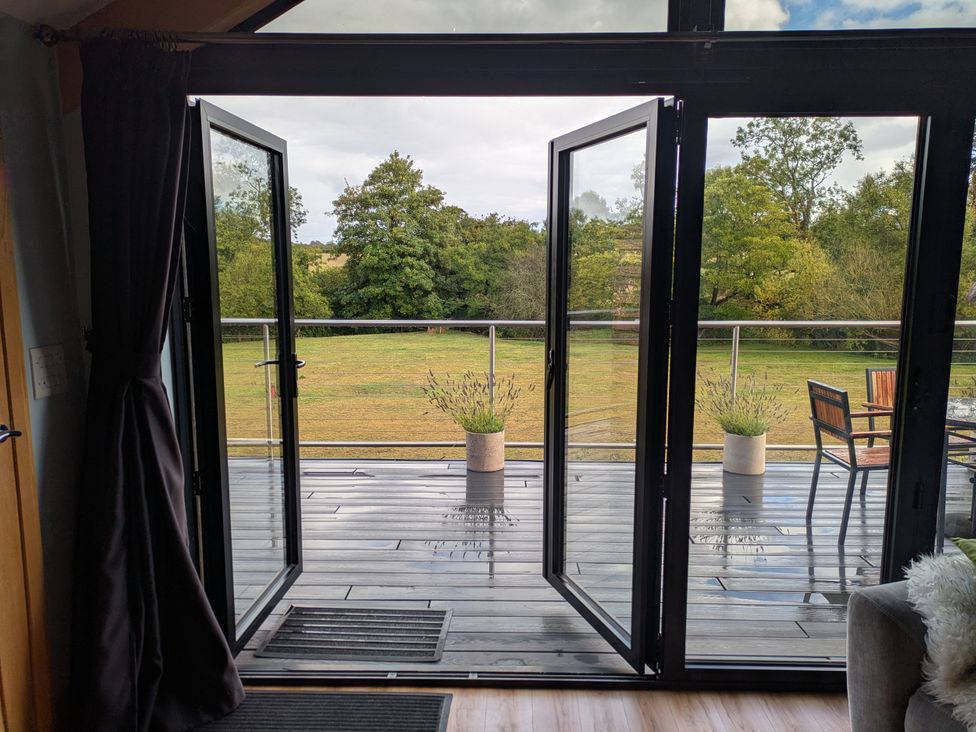Sliding doors opening to a wooden deck with planters at Cointree in Sturminster Newton