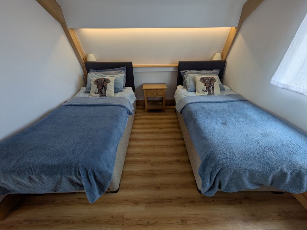 A bedroom with two beds and a bedside table at Cointree Sturminster Newton