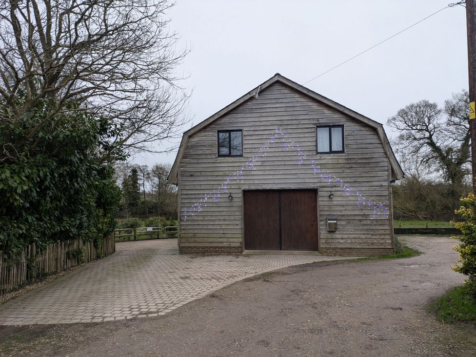 A wooden building with garage doors and a pathway at Cointree in Sturminster Newton