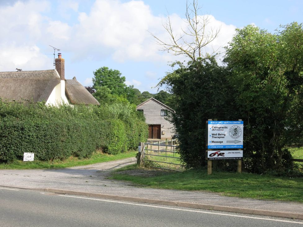 A house with a thatched roof and a sign for Rolls Mill Health Centre in Sturminster Newton