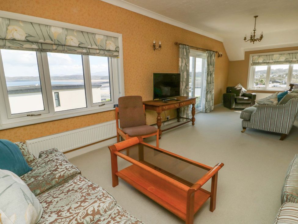 A living room with a window, sofa, armchair and coffee table at Bryn y Don in Benllech