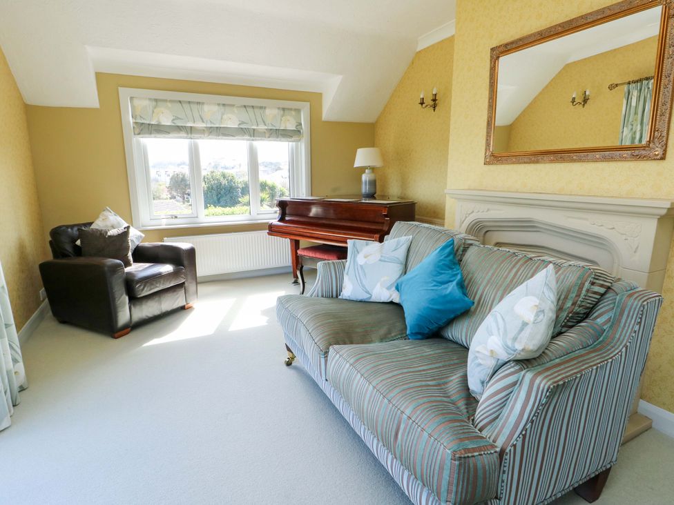 A living room with a piano and armchair at Bryn y Don in Benllech