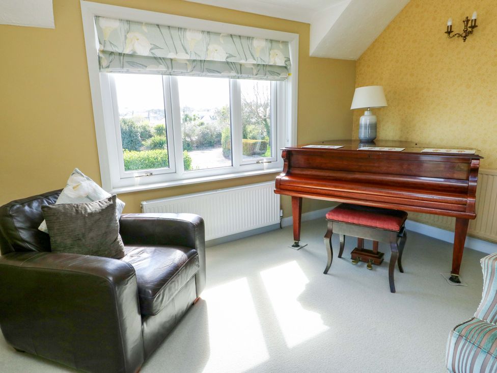 A snug with a piano and an armchair at Bryn y Don in Benllech
