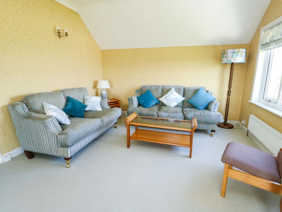 A living room with a sofa, chair, and coffee table at Bryn y Don in Benllech