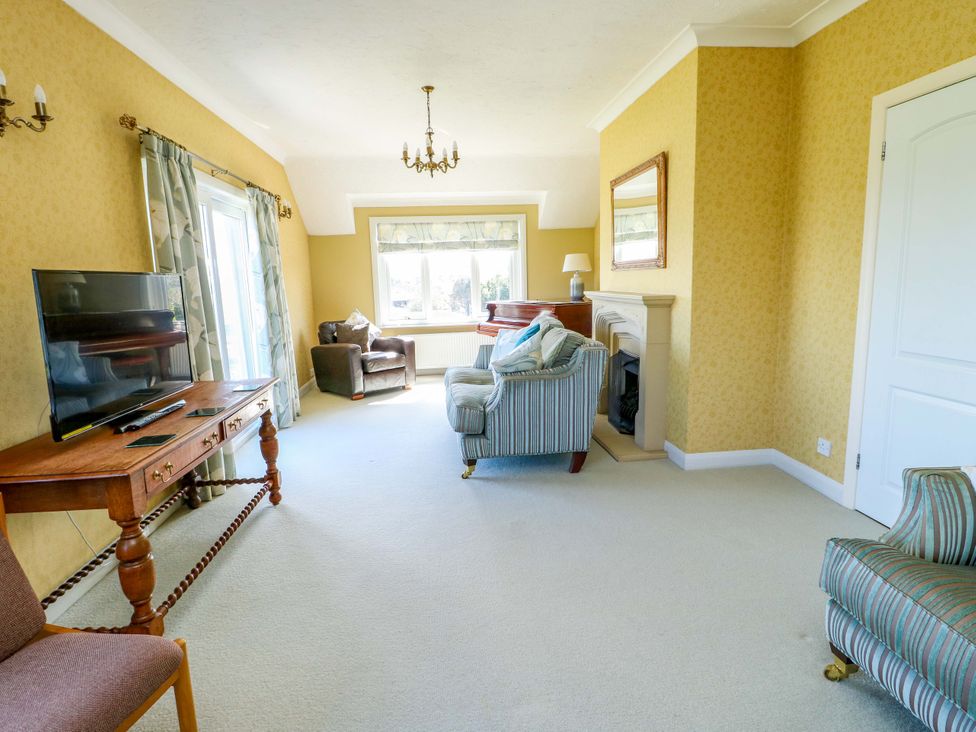 A living room with a television and a sofa at Bryn y Don in Benllech