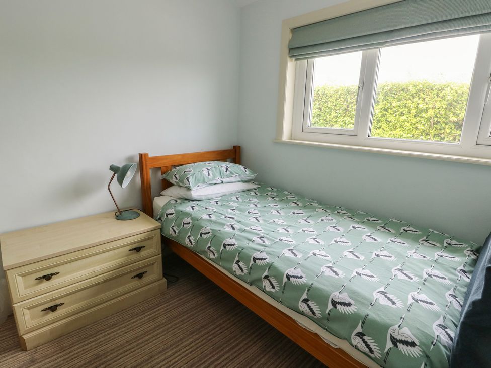 A bedroom with a bed and chest of drawers at Bryn y Don in Benllech