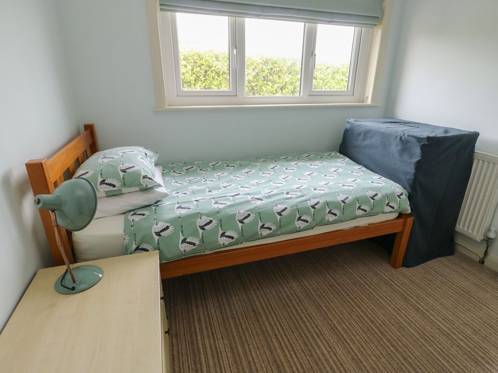 A bedroom with a bed and a bedside lamp at Bryn y Don in Benllech