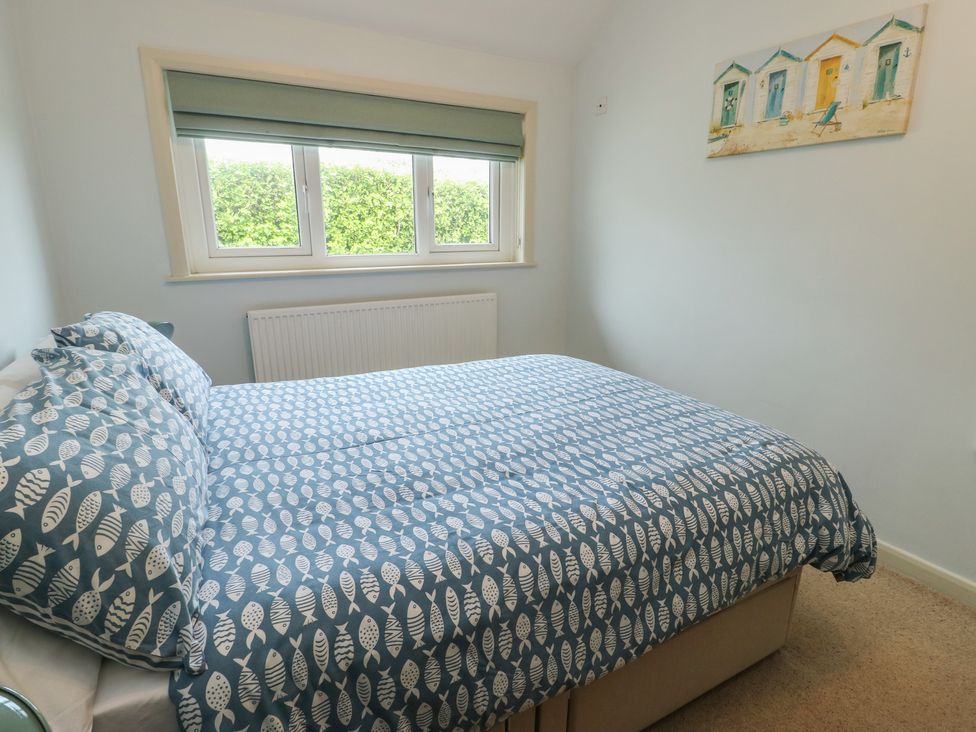 A bedroom with a bed and window at Bryn y Don in Benllech