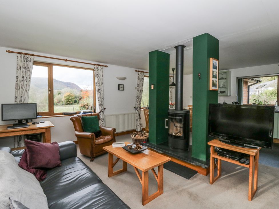 A living room with a wood stove and television at Geryllan, Rhandirmwyn near Llandovery