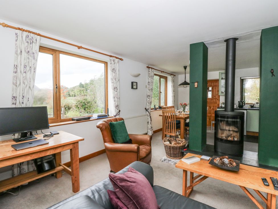 A living room with a computer and a fireplace at Geryllan Rhandirmwyn near Llandovery