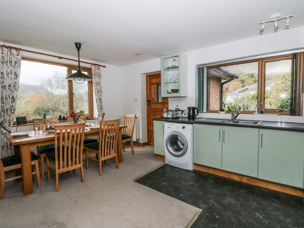 A kitchen with a dining table and washing machine at Geryllan Rhandirmwyn near Llandovery