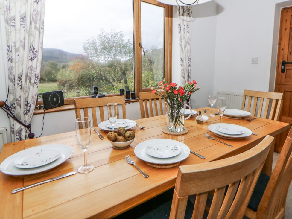 A dining room with a wooden table and chairs at Geryllan Rhandirmwyn near Llandovery
