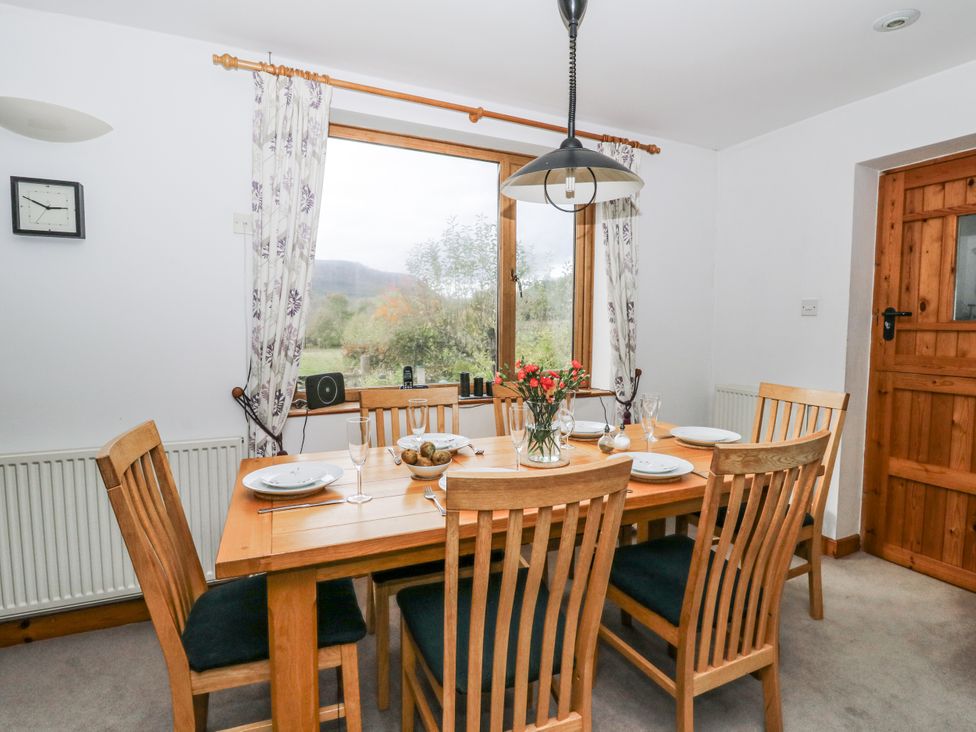 A dining room with a wooden table and chairs at Geryllan Rhandirmwyn near Llandovery