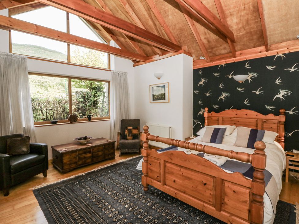 A bedroom with a wooden bed and a window at Geryllan Rhandirmwyn near Llandovery