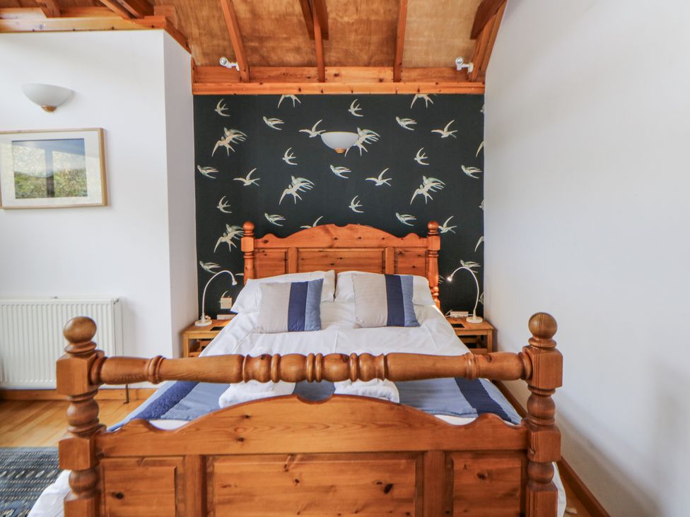 A bedroom with a wooden bed and bedside table at Geryllan Rhandirmwyn near Llandovery