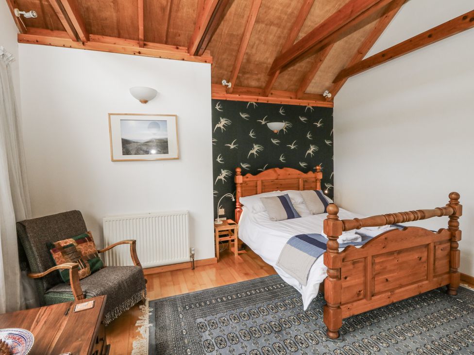 A bedroom with a bed and chair at Geryllan Rhandirmwyn near Llandovery