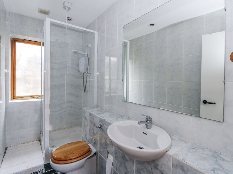A bathroom featuring a toilet, sink, shower, and mirror at Geryllan, Rhandirmwyn near Llandovery