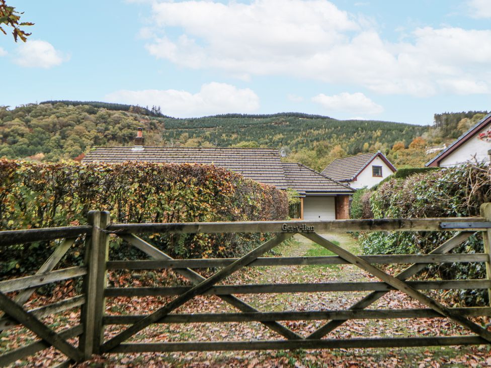 A view of a gate leading to houses and mountains at Geryllan, Rhandirmwyn near Llandovery