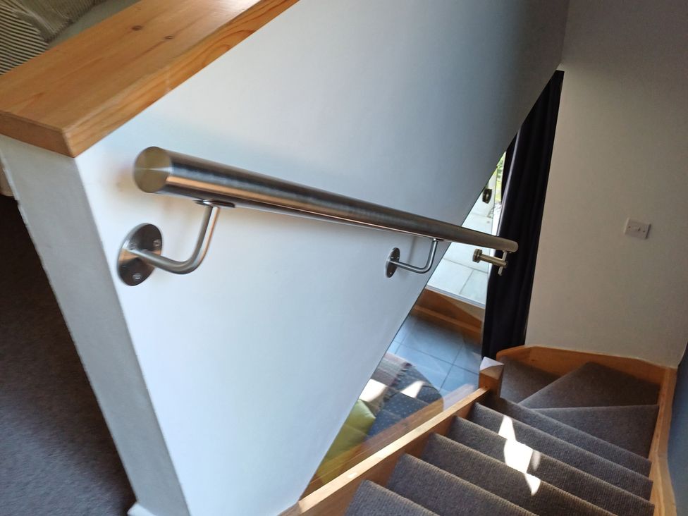 A staircase with a handrail and door at The Sidings in Wirksworth