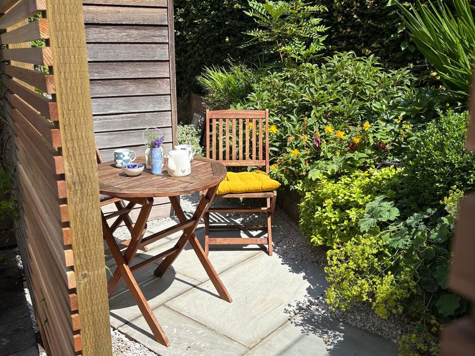 A garden with a table and chair set surrounded by plants at The Sidings in Wirksworth