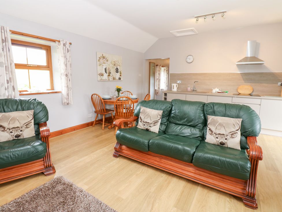 A living room with a sofa and dining area at The Hayloft in Alston